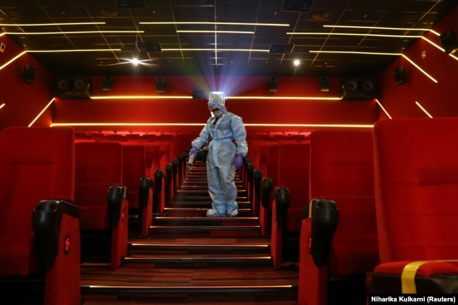 Një punëtor dezinfekton një kinema.