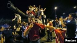 People stand on a Turkish Army tank at Ataturk airport in Istanbul in the early morning hours of July 16.