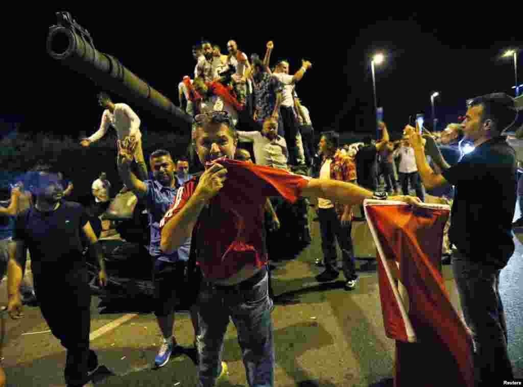 People stand on a Turkish Army tank at Ataturk airport in Istanbul.