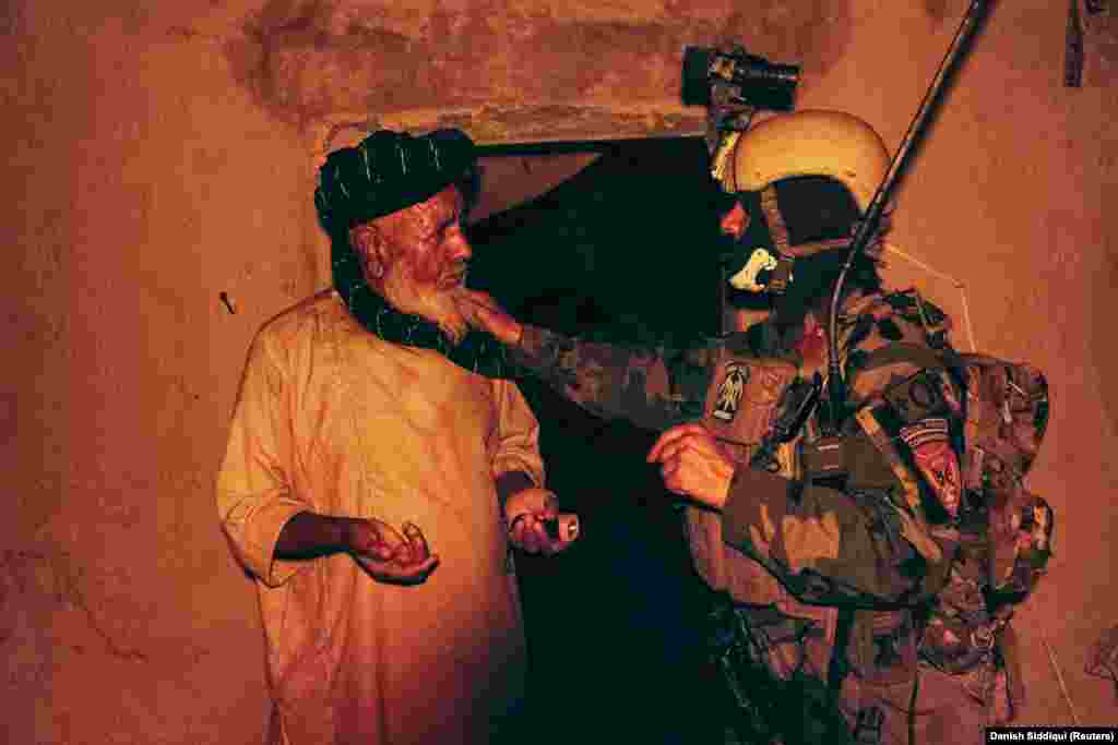 A special forces soldier speaks to a resident as others search his house during the anti-Taliban operation on July 12.&nbsp;