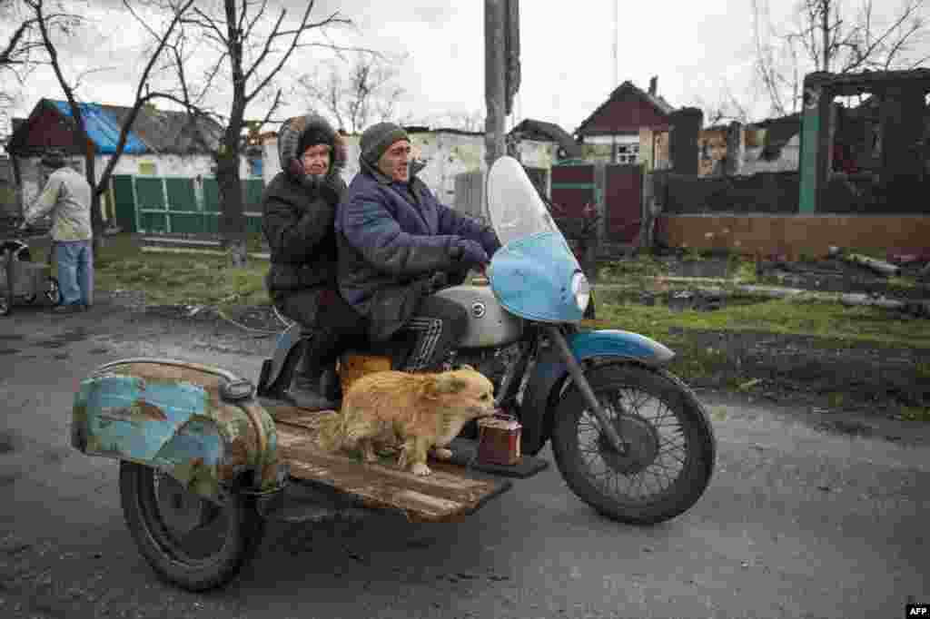 Жінка з чоловіком та собакою їде вулицею зруйнованого під час боїв села Нікішине, неподалік Дебальцевого, 21 квітня 2015 року