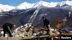 Workers clean an area next to an unfinished hotel in the mountain media village on top of the village of Esto Sadok at the Rosa Khutor alpine resort near Sochi on February 2, less than a week before the opening of the 2014 Winter Olympics.