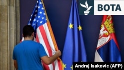 Një punonjës rregullon flamurin amerikan pranë flamurit të BE-së dhe atij serb, në prag të një konference të përbashkët për shtyp të zyrtarëve serbë dhe amerikanë në Beograd, nëntor 2019.