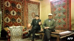 Iranian men sit in their Persian carpet shop in Tehran's old bazaar 12 February 2000. Iran is one of the world's biggest exporters of carpets. / AFP PHOTO / PATRICK BAZ