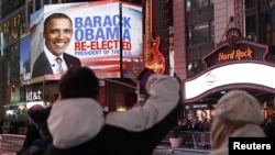 Люди смотрят на плакат с надписью: "Барак Обама переизбран". Нью-Йорк, 6 ноября 2012 года. 