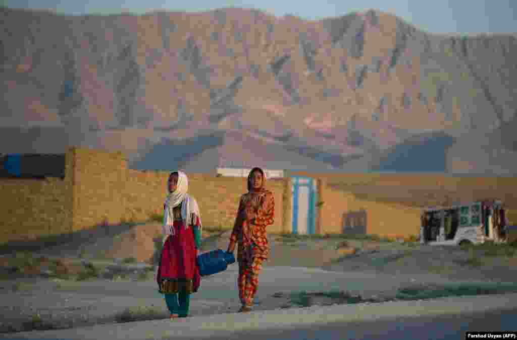 Afghan girls carry a gas canister on the outskirts of Mazar-e Sharif. (AFP/Farshad Usyan)