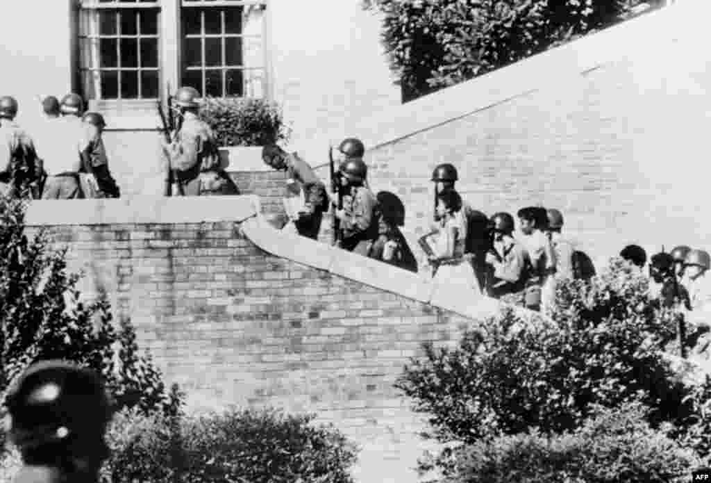 Nine black children are escorted by U.S. paratroopers outside a school in Little Rock, Arkansas, on September 25, 1957. U.S. President Dwight D. Eisenhower had ordered government troops to protect the children from angry protesters as they began attending a white-majority school. The state&#39;s governor, Orval Faubus, had ordered the state militia to bar the children from entering the school.