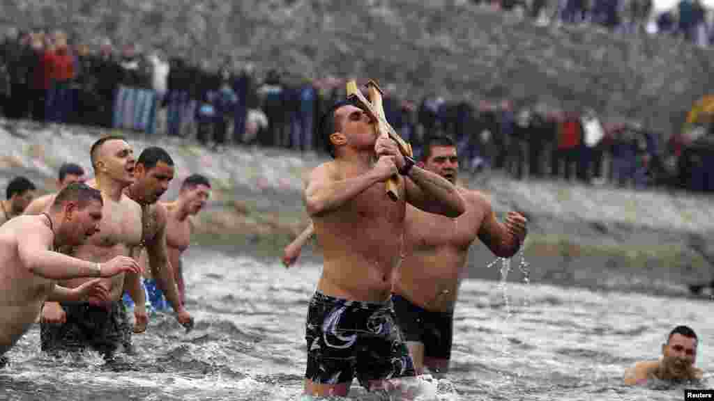 A man kisses a wooden cross that he managed to catch after it was thrown by a priest into the waters of the Nisava River during Orthodox Christian Epiphany celebrations in Nis, Serbia, on January 19. (REUTERS/Stoyan Nenov)