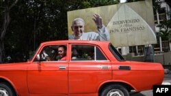 Советский автомобиль "Москвич" проезжает мимо плаката, приветствующего Папу Римского Франциска. Гавана, Куба, 16 сентября 2015 года.