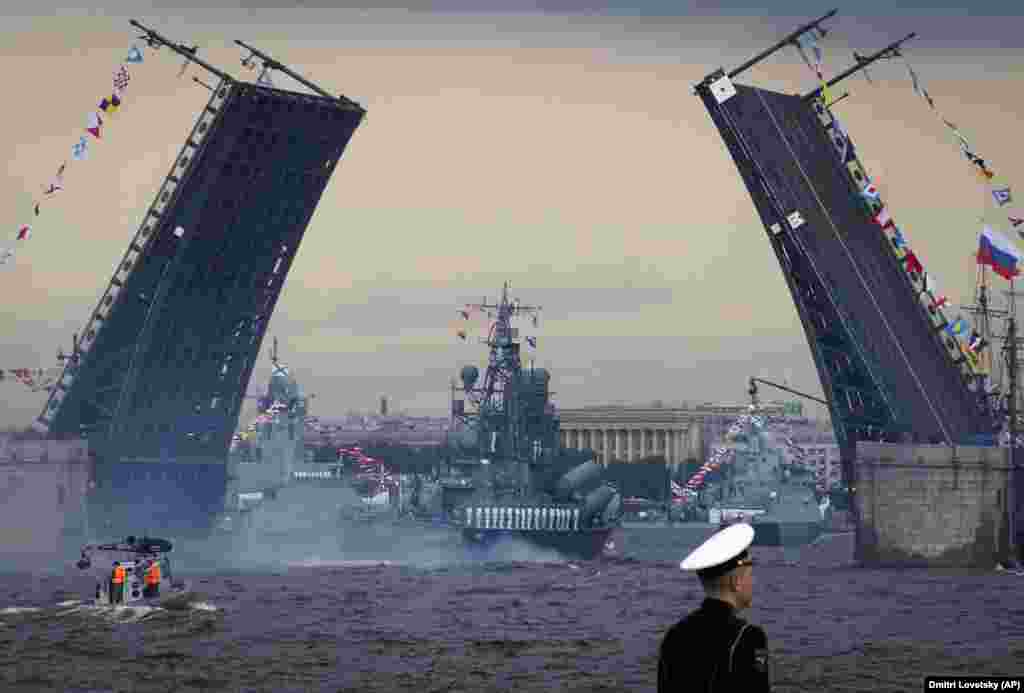 Warships float past a drawbridge rising above the Neva River during the Navy Day parade in St.Petersburg, Russia, on July 28. (AP/Dmitri Lovetsky)
