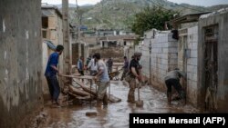 IRAN -- Men clear away mud following floods in the Iranian city of Mamulan in Lorestan province, April 7, 2019