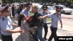 Полицейские задерживают участницу акции протеста проблемных заемщиков ипотечных кредитов у здания АТФ банка. Алматы, 15 июля 2014 года. 