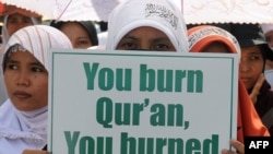 Участница протеста против сожжения Корана держит плакат с надписью "Сжигаешь Коран, гореть тебе в аду". Джакарта, Индонезия, 4 сентября 2010 года.