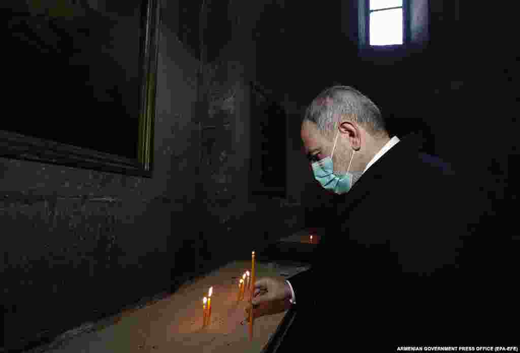 Pashinian lights a candle inside a church in a military cemetery in Sisian on December 21. The Armenian prime minister was openly snubbed by a priest&nbsp;who refused to shake his hand and appeared to usher him out of the Sisian church.