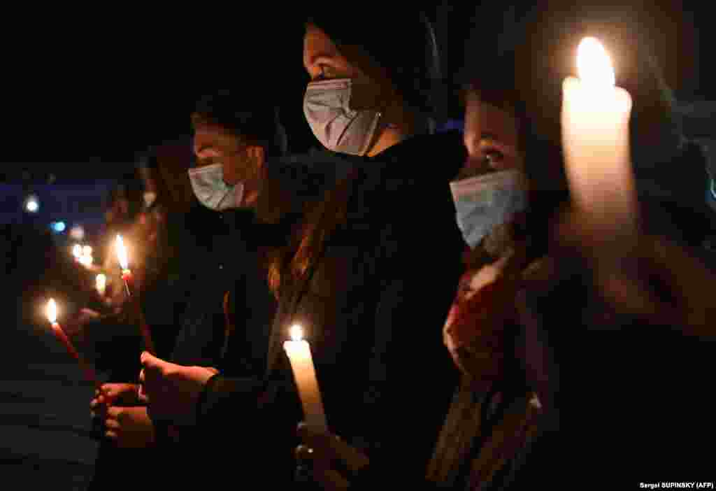 People hold candles at a monument to Chernobyl victims in the city of Slavutych.