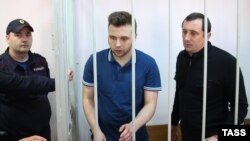 Defendants Aleksandr Margolin (right) and Ilya Guschin (center) stand in a cage during a hearing in the Bolotnaya case in a courtroom in Moscow in May.