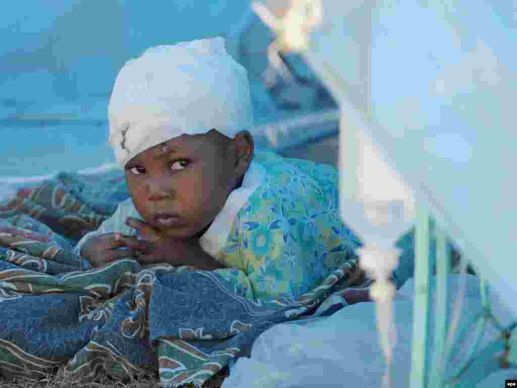 A Haitian child injured by the earthquake receives medical treatment at a hospital run by a relief organisation. - A week after the devastating earthquake on January 12, aid groups were still struggling to get food, water, and medical help to the survivors, as frustration grew over the slow pace of the relief efforts. Photo by Federico Gambarini for epa