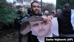 A man tears up a photo of Syrian President Bashar al-Assad in front of the Syrian Embassy in Belgrade on December 8.