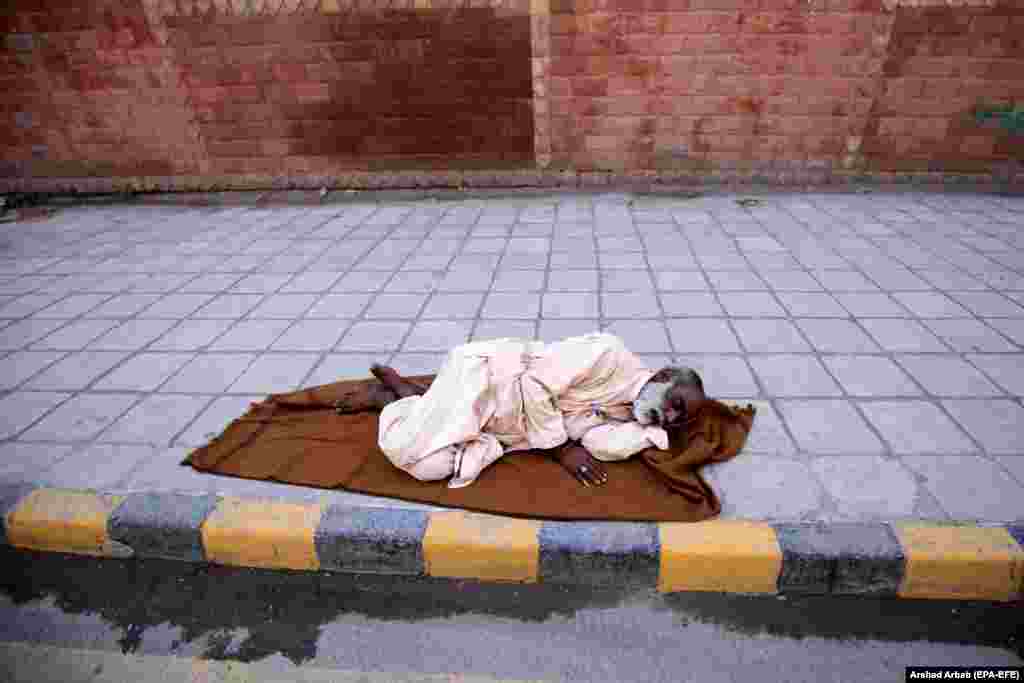 An elderly Pakistani man sleeps on a roadside in Peshawar. (epa-EFE/Arshad Arbab)