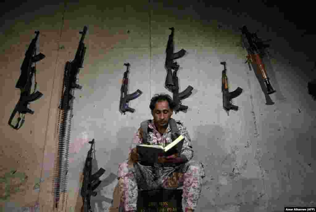 A Syrian rebel fighter reads the Koran as he sits in a fortified position in a suburb of Aleppo. (AFP/Amer Al-Hamwe)