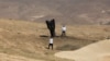 A man poses for a photo next to a fallen rocket half-buried in the ground on the outskirts of Jericho on June 8, 2026, following Iranian and Iran-backed Houthi rebel attacks.