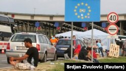 Migrants gather near a European Union sign at the Croatia-Slovenia border crossing at Bregana, Croatia, on September 19.