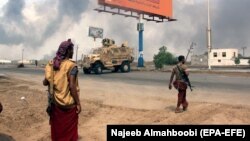 Yemeni government forces patrol as smoke billows from an alleged Huthi position during battles between Yemeni government forces and Huthi rebels in the port city of Hodeidah in September 2018.