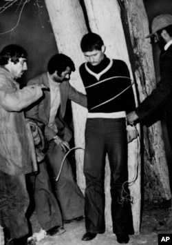An Iranian military police sergeant is tied to a tree for execution by a revolutionary committee firing squad in Qazvin, Iran, March 3, 1979.