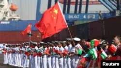 Chinese families along with Pakistani Navy servicemen wave flags to welcome a Chinese naval vessel upon its arrival to participate in an exercise in Karachi in February.