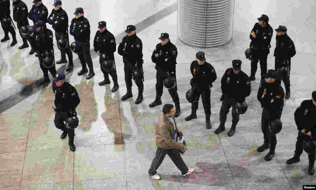 A passenger passes a line of police at Atocha rail station during a 24-hour nationwide general strike in Madrid. Spanish and Portuguese workers staged the first coordinated strike across the Iberian peninsula on November 14, shutting down transport, grounding flights, and closing schools to protest austerity measures and tax hikes. (Reuters/Paul Hanna)