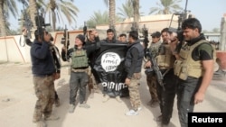 Iraqi security forces pose with an Islamic State flag that they pulled down in the city of Ramadi in January.