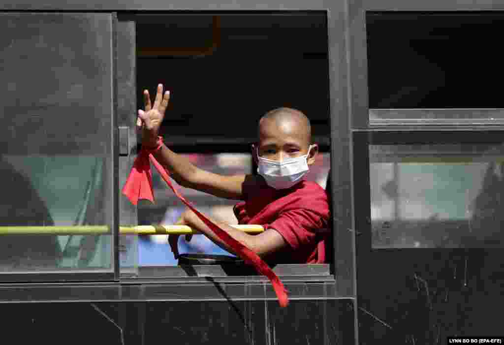 Un tânăr budist, purtând o fâșie de pânză roșie în jurul încheieturii mâinii, arată un salut cu trei degete, simbol al rezistenței împotriva loviturii de stat militare 