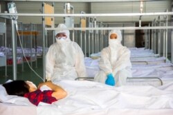 Коронавирус науқасына қарап отырған мейіргерлер.