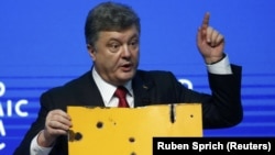 Виступ президента України Петра Порошенка в Давосі у 2015 році. Порошенко демонструє прошиту, як він стверджує, на Донбасі російською ракетою частину автобуса, що перевозив цивільних