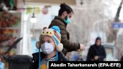 An Iranian child wearing face mask walks on a street of Tehran, February 26, 2020