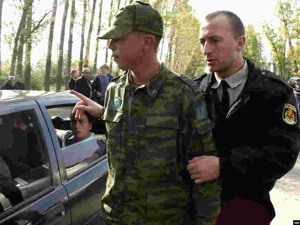 Грузинский полицейский сопровождает солдата, задержанного на территории Грузии, на блокпост вооруженных сил РФ, Надарбазеви (70 км. от Тбилиси), 8 октября 2008.