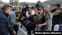 Migranti pomažu ženi koja je dobila ozljede tijekom intervencije hrvatskih policajaca na hrvatsko-bosanskohercegovačkoj granici, 24. listopada