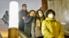 Люди у захисних масках спускаються на ескалаторі в метро (ілюстративне фото)