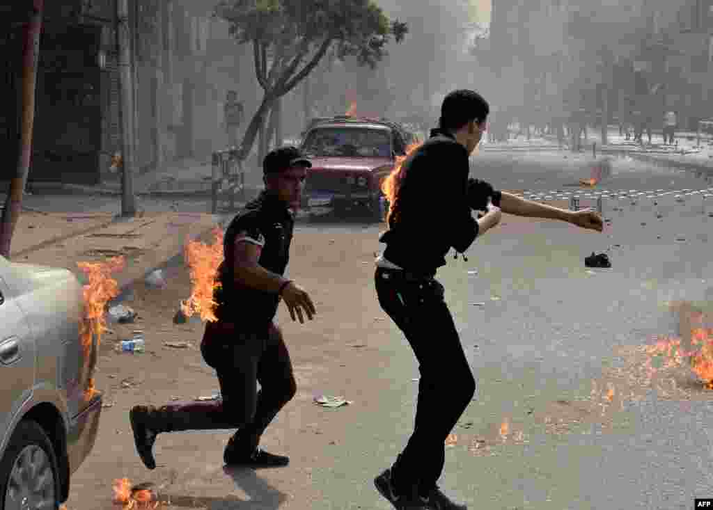 Coptic Christians try to put out their burning clothes after they were attacked by unidentified individuals outside the cathedral in the central Cairo neighbourhood of Abbassiya. (AFP/Mohammed al-Shahed)