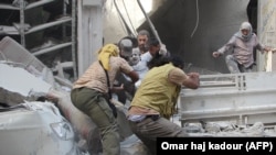 Syrian men evacuate a victim from the rubble of a building following a reported air strike on the rebel-held northwestern city of Idlib on September 10.
