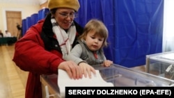 یک خانم در حال ریختن رأی اش به صندوق در یکی از محلات رأی‌دهی در کیف پایتخت اوکراین ۳۱ مارچ ۲۰۱۹ / EPA-EFE/SERGEY DOLZHENKO