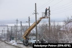 Украинские рабочие ремонтируют линию электропередачи, поврежденную во время обстрела в Новолуганске