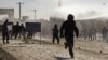 An Afghan policeman flees as protesters throw rocks near a U.S. military base in Kabul on February 22, the second day of unrest after reports that NATO troops had burned copies of the Muslim holy book.