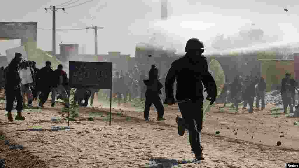 An Afghan policeman flees as protesters throw rocks near a U.S. military base in Kabul on February 22, the second day of unrest after reports that NATO troops had burned copies of the Muslim holy book.