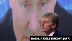 Пресс-секретарь президента РФ Дмитрий Песков на фоне экрана с изображением Владимира Путина
