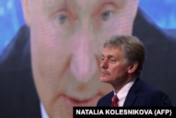 Purtătorul de cuvânt al Kremlinului, Dmitri Peskov, a cărui imagine este proiectată pe cea a președintelui rus, Vladimir Putin.