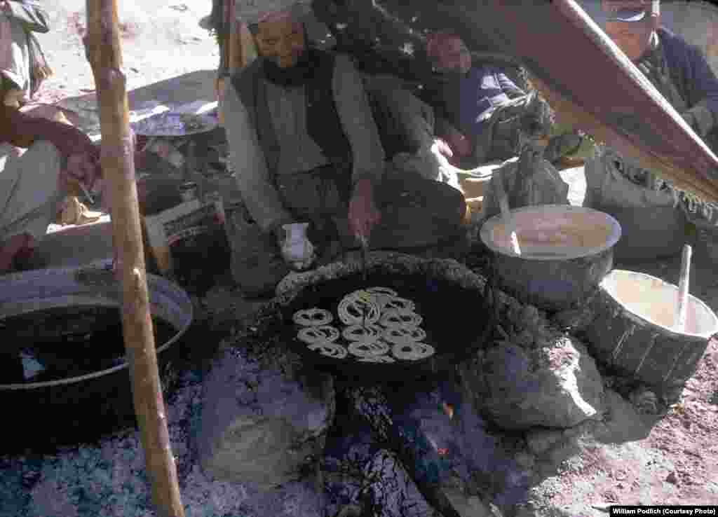 A merchant fries jalebi, a sweet Afghan dessert, over an open fire.