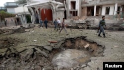 Afghan policemen walk past a crater at the site of a suicide attack at the Indian Consulate in Jalalabad on August 3. 