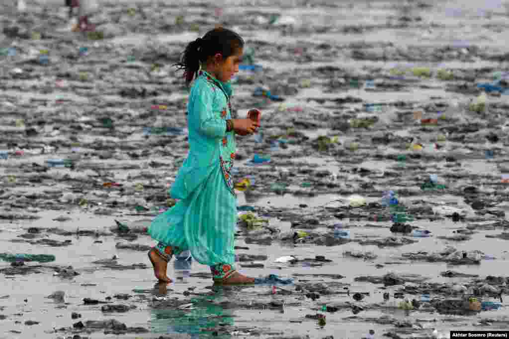 Дзяўчынка ідзе па засьмечаным пляжы ў Карачы, Пакістан.