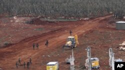 An Israeli military digger works on the Lebanese-Israeli border next to a wall that was built by Israel in the southern village of Kafr Kila, Lebanon, Tuesday, Dec. 4, 2018. The Israeli military launched an operation on Tuesday to "expose and thwart" tunn